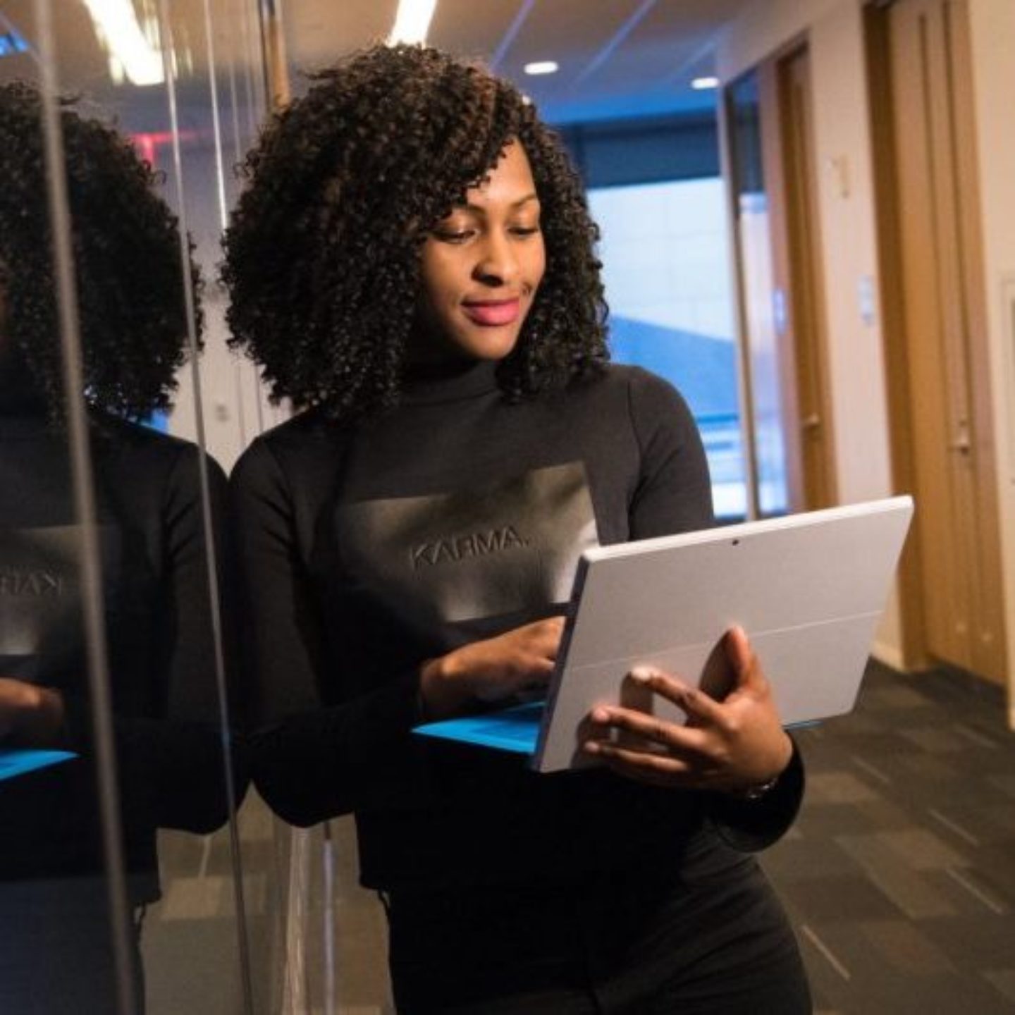 Woman of color with her laptop in front of computer server.