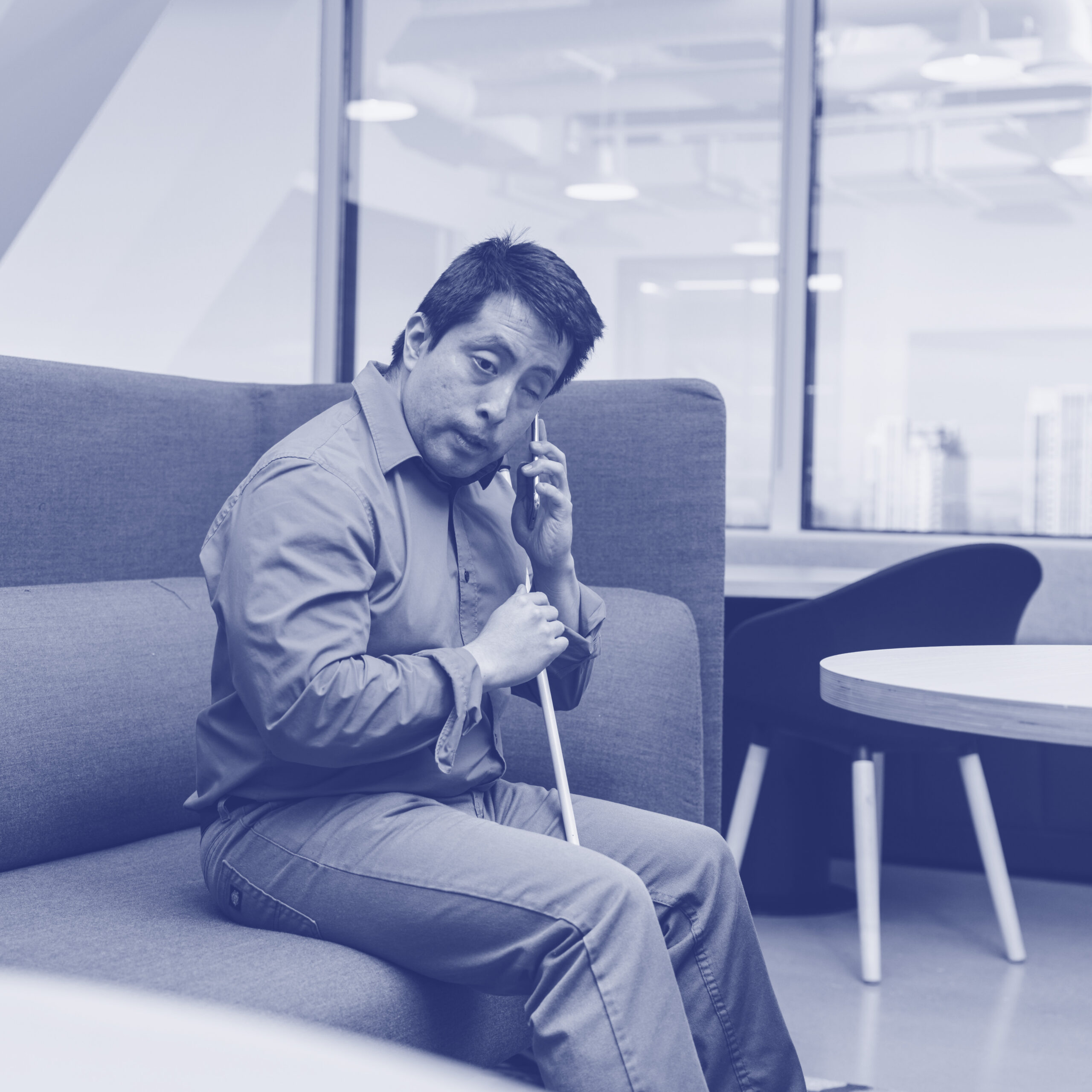 Israel Listens to his Phone_navy Israel, a Blind man, listens to his phone at a corporate office booth.